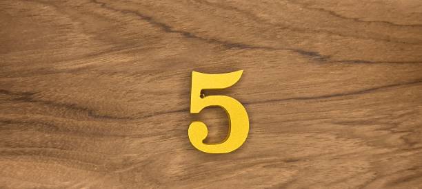 istock Golden number 5 on wooden background 2204545012