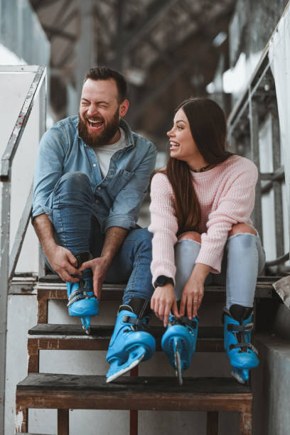 istock Joyful Couple Laughing Loudly While Fastening Figure Skates Before Practice 2204547433