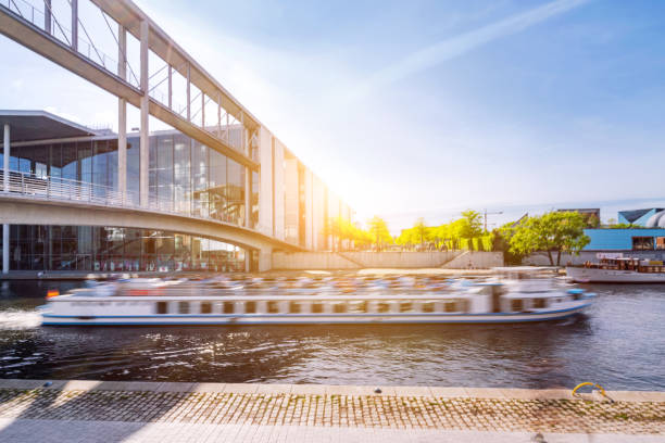 istock Blurred Tourist Boat Passing Modern Building Along Berlin River at Sunset 2204548540