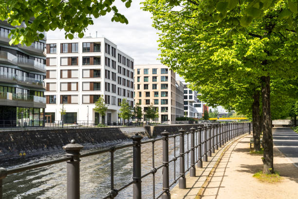 istock Modern Buildings Along a Tree-Lined Riverbank Under a Bright Summer Sky 2204548640