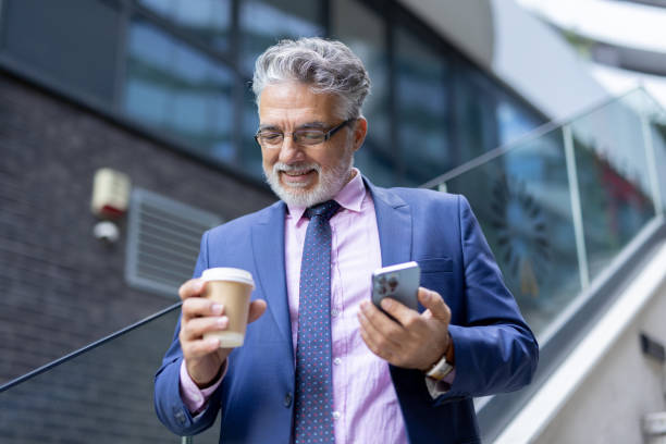 istock Businessman Smiling at Phone with Coffee in Modern Setting 2204549113