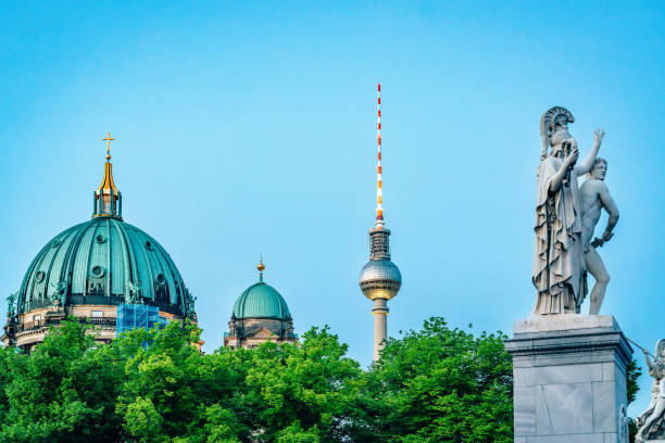 Iconic Berlin landmarks captured under a bright sky, including the Berlin Cathedral, the Fernsehturm TV Tower, and an elegant statue amidst greenery.