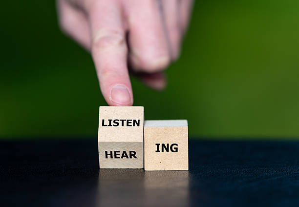 istock Hand turns cube and changes the word hearing to listening. 2204550337