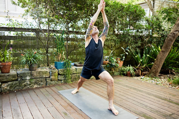 istock Senior man doing Warrior I position on outdoor deck 2204552110