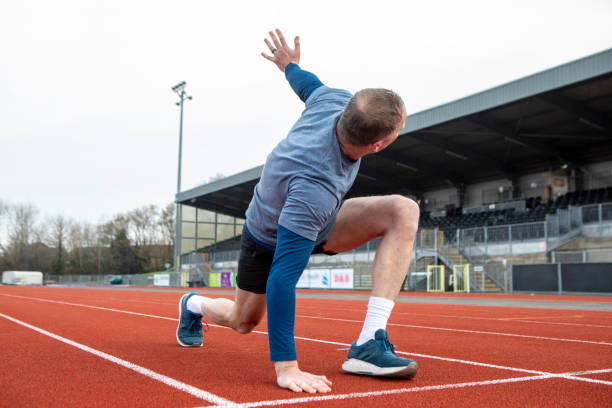 istock Mature male athlete doing a stretch exercise on a running track 2204554032