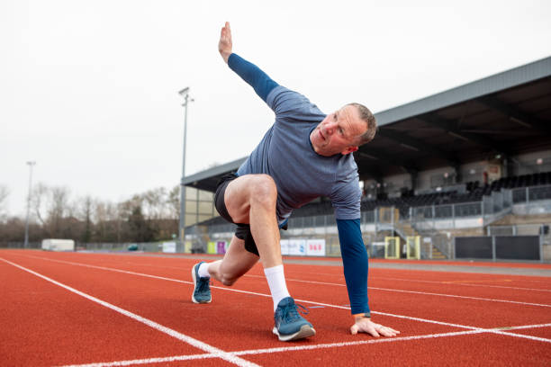 istock Mature male athlete doing a stretch exercise on a running track 2204554059