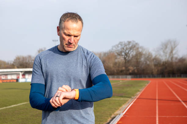 Mature male athlete setting a smart watch on a running track