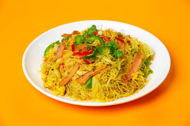 istock Singapore Fried Rice Noodles including rice vermicelli stir fried with ham, vegetables, cilantro and red chilies served in plate isolated on orange background side view of hong kong food 2204559862
