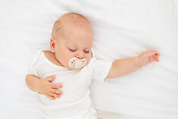istock cute little newborn baby sleeping with a pacifier in his mouth under a blanket hugging a plush bunny, sweet healthy baby sleep in a white crib 2204560368