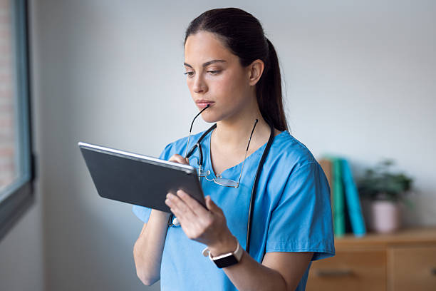istock Female nurse using her digital tablet while standing in the consultation 2204565369