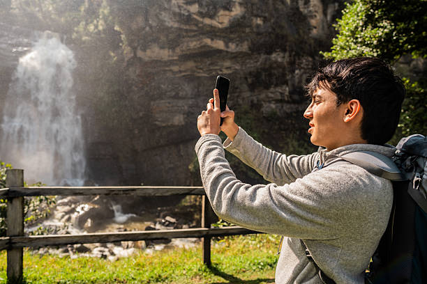 istock Young man taking photos of waterfall 2204569897