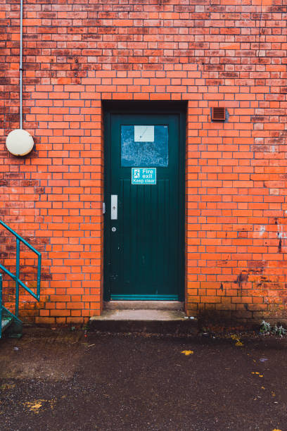 Green fire exit door in a red brick wall in bristol, england