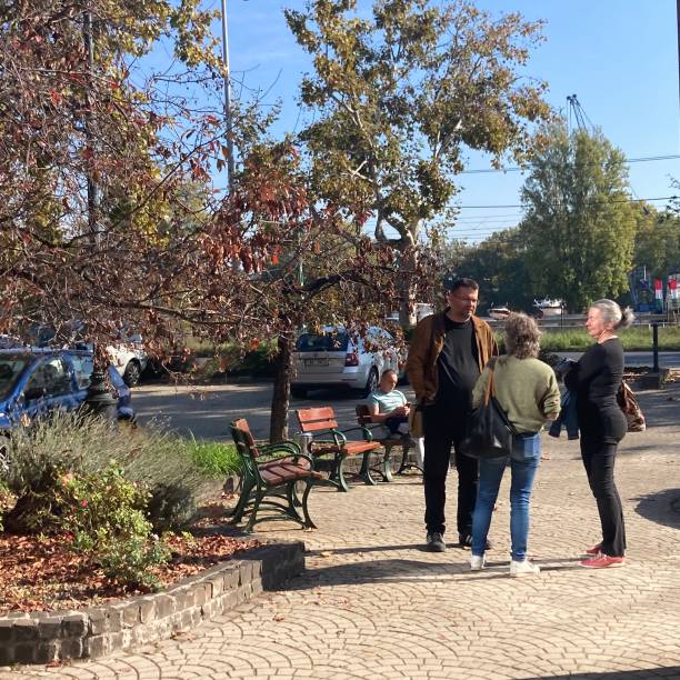 10/16/2022. Budapest . Hungary.\n\n3 people having a chat enjoying the autumn sun in the street in Budapest. Hungary.