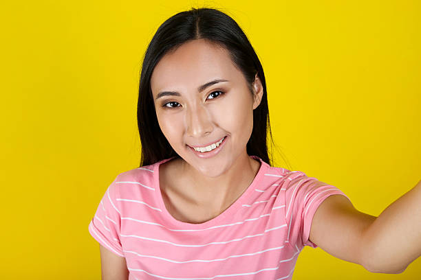 istock Beautiful woman making selfie on yellow background 2204572355