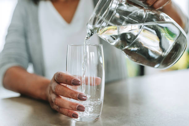 istock Woman pouring cup water on glass 2204573029