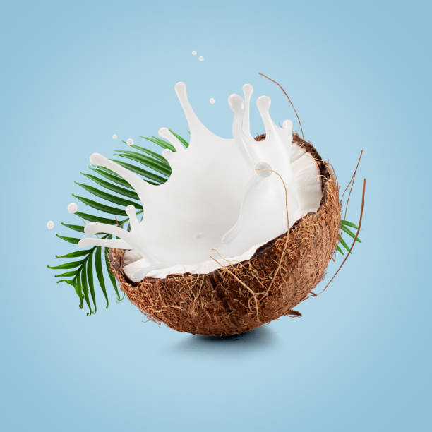 istock coconut with palm leaf and milk splash on a light blue background 2204573264
