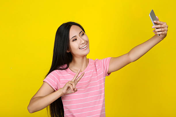 istock Young woman making selfie on smartphone on yellow background 2204574198
