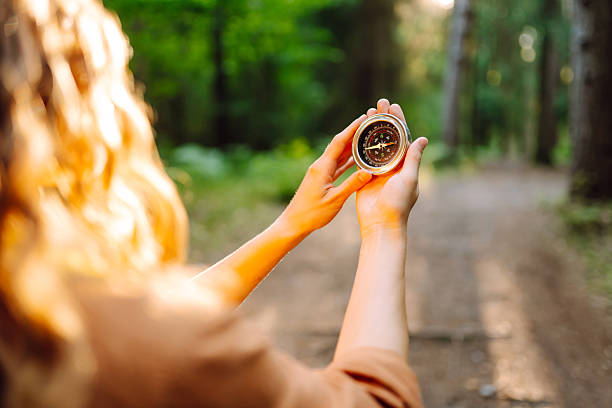 istock Close-up of hiker's hands holding a compass against a forest trail. 2204575867