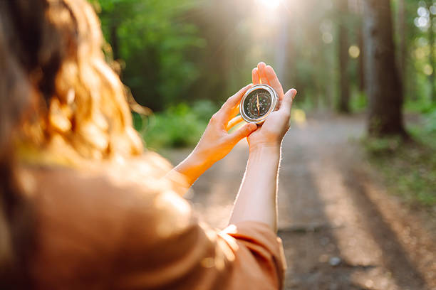 istock Close-up of hiker's hands holding a compass against a forest trail. 2204575870