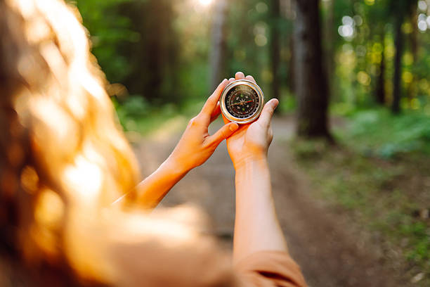 istock Close-up of hiker's hands holding a compass against a forest trail. 2204575874