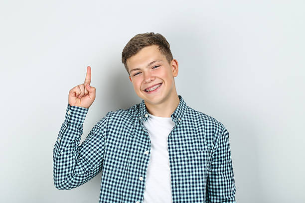 istock Young man with dental braces showing finger up on grey background 2204576108