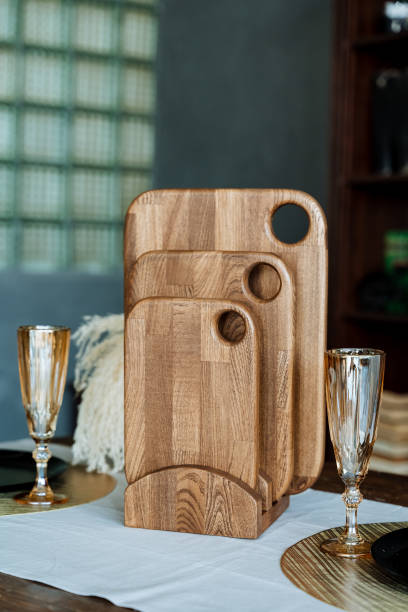 Three beautifully crafted wooden cutting boards are thoughtfully stacked on top of one another upon a sturdy table, showcasing their unique designs and rich wood grain patterns