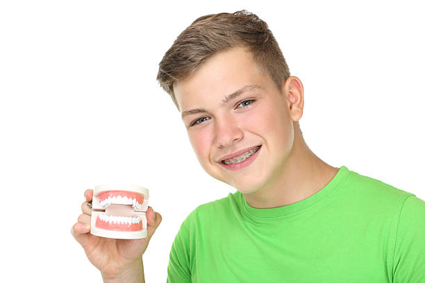 istock Young man with dental braces holding teeth model on white background 2204577068