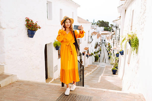 istock Cheerful woman taking selfie on phone while walking in old town. 2204577861