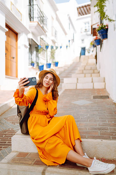 istock Cheerful woman taking selfie on phone while walking in old town. 2204577875