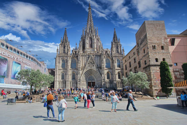 Barcelona, Spain - May 21, 2015: Tourists sit on the stairs in front of the Cathedral of Barcelona, Spain on May 21, 2015.