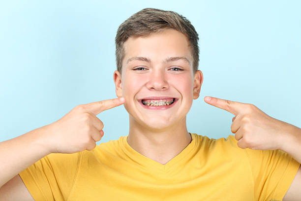 istock Young man pointing on dental braces on blue background 2204579003