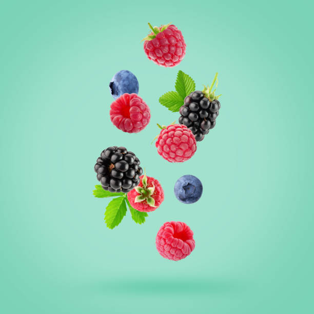 istock falling raspberries, blackberries and blueberries on a light green background 2204579049
