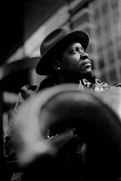 Grainy black and white portrait capturing a thoughtful musician wearing a stylish hat, gazing upwards with a sense of hope and deep contemplation, embodying artistic expression and emotion