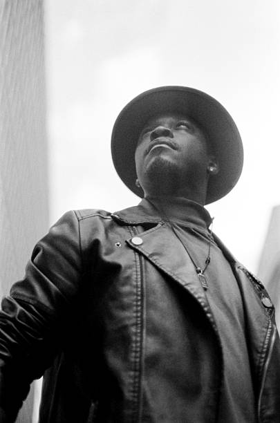 istock Stylish man wearing hat and leather jacket looking up in black and white 2204579497