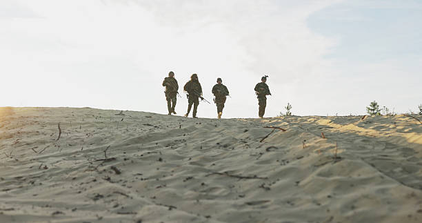 Soldiers in uniform descend from the observation post, ending their duty shift, rifles in hand, helmets on, as they rotate positions in a territorial defense field exercise.
