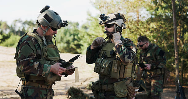 istock Soldiers from a powerful army prepare a battle strategy, entering data into the system, discussing tactics, and organizing equipment while dressed in camouflage uniforms and helmets at the training ground. 2204581464