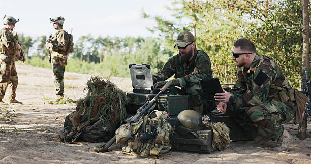 istock Soldiers from a powerful army prepare a battle strategy, entering data into the system, discussing tactics, and holding a tablet while dressed in camouflage uniforms, helmets, and backpacks at the training ground. 2204581483