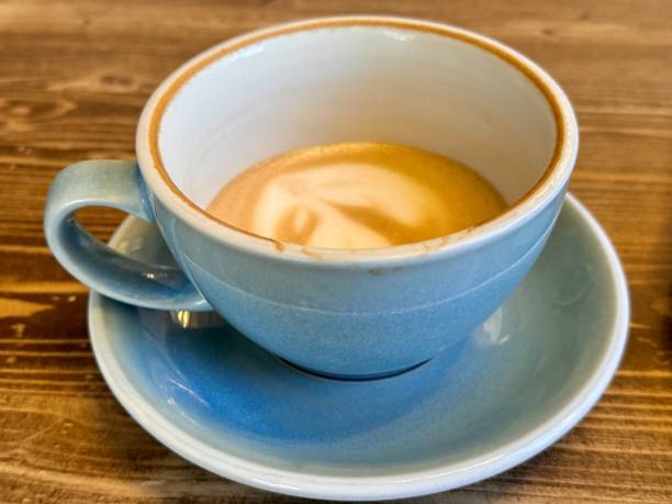 istock Magnificent latte art in a charming blue cup on a cozy wooden table. A half-drunk latte by a customer in a bright blue cup on a wooden surface 2204582627
