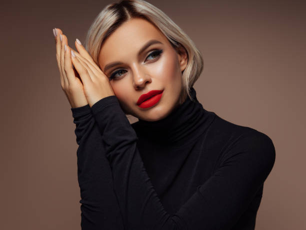 istock Elegant woman with red lips posing against a brown gradient background 2204582895