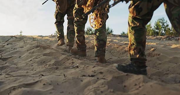 istock Soldiers march on sandy terrain during a field exercise, their military boots leaving deep tracks as they patrol the area, weapons in hand, ready for action. 2204583140