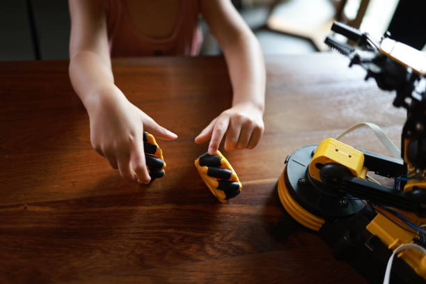 Cute girl enjoying playing with a robotic car. elementary girl learning control robotic car science lesson at house . Girl Pupil learning to Building Robot Arm