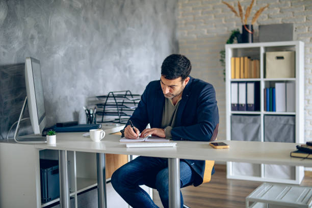 istock Handsome businessman doing paper work in his office 2204583772