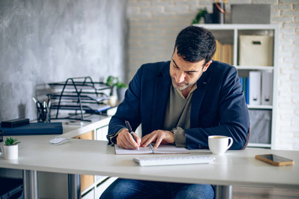 istock Handsome businessman doing paper work in his office 2204583907