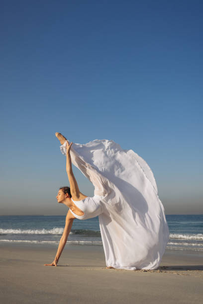 istock Graceful dancer performing a ballet pose on a sunlit beach 2204585868