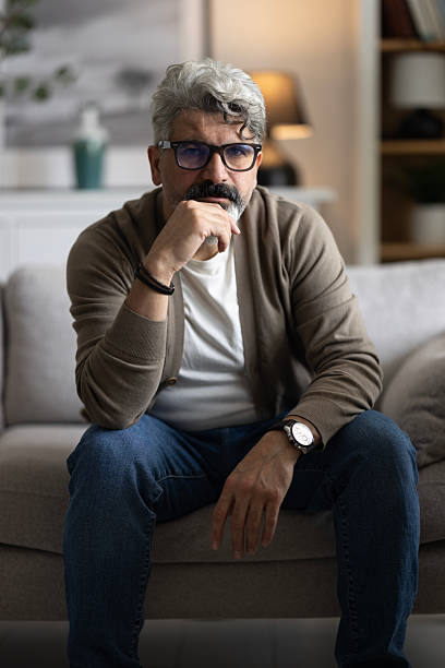 istock Thoughtful serious man sitting on sofa at home, lost in thoughts 2204588245