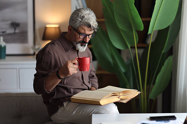 istock Mid adult man reading book in the library 2204589214