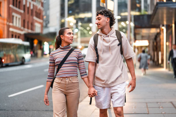 istock Young Hispanic Couple Strolling Sydney Streets at Dusk 2204591607