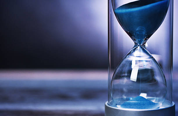 istock Blue sand flowing through hourglass measuring time passing by. 2204593477