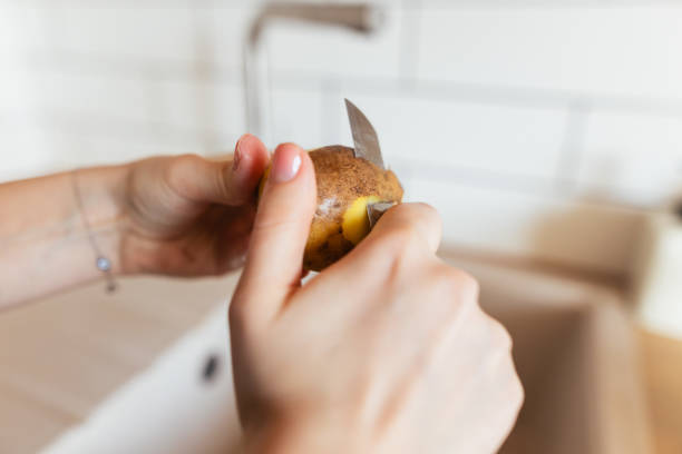 Hands of a man peeling cooked potatoes in the kitchen, preparation for cooking a healthy meal, selected focus, narrow depth of field