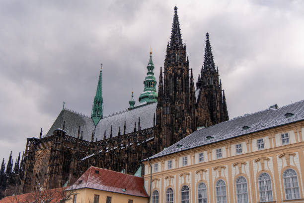 02-21-2025, Prague, St. Vitus Cathedral's gothic spires and snow-covered roof dominate the Prague Castle complex on a cloudy winter day, showcasing the city's rich history and stunning architecture